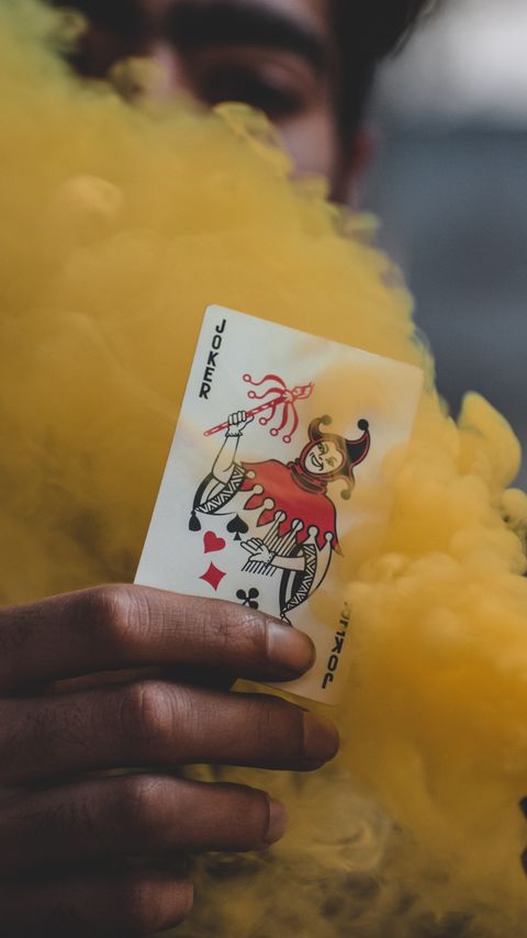 Download wallpaper 2160x3840 joker, playing card, smoke, yellow, hand samsung galaxy s4, s5, note, sony xperia z, z1, z2, z3, htc one, lenovo vibe hd background